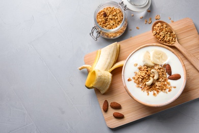 Tasty breakfast with yogurt, banana and granola on table, top view