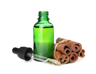 Photo of Bottle of essential oil and cinnamon sticks on white background