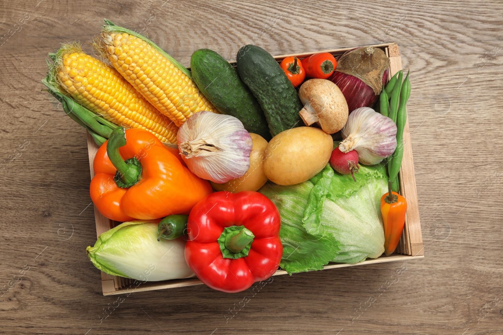 Photo of Crate with different fresh vegetables on wooden background, top view