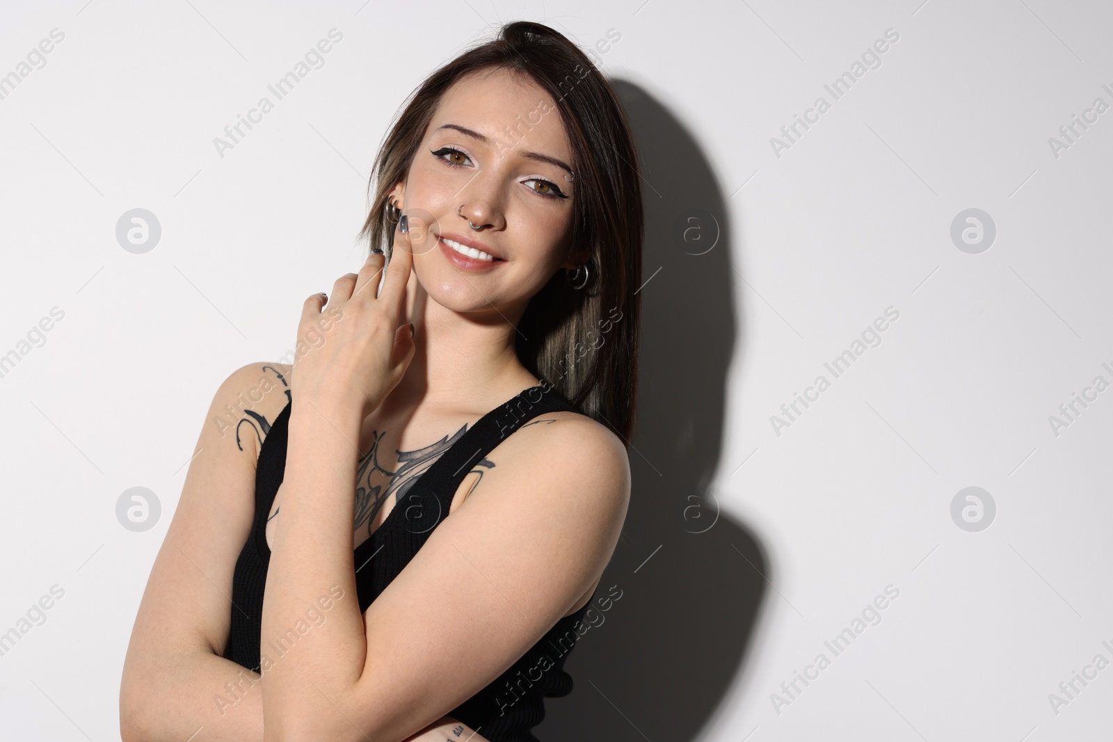 Photo of Portrait of smiling tattooed woman on light background