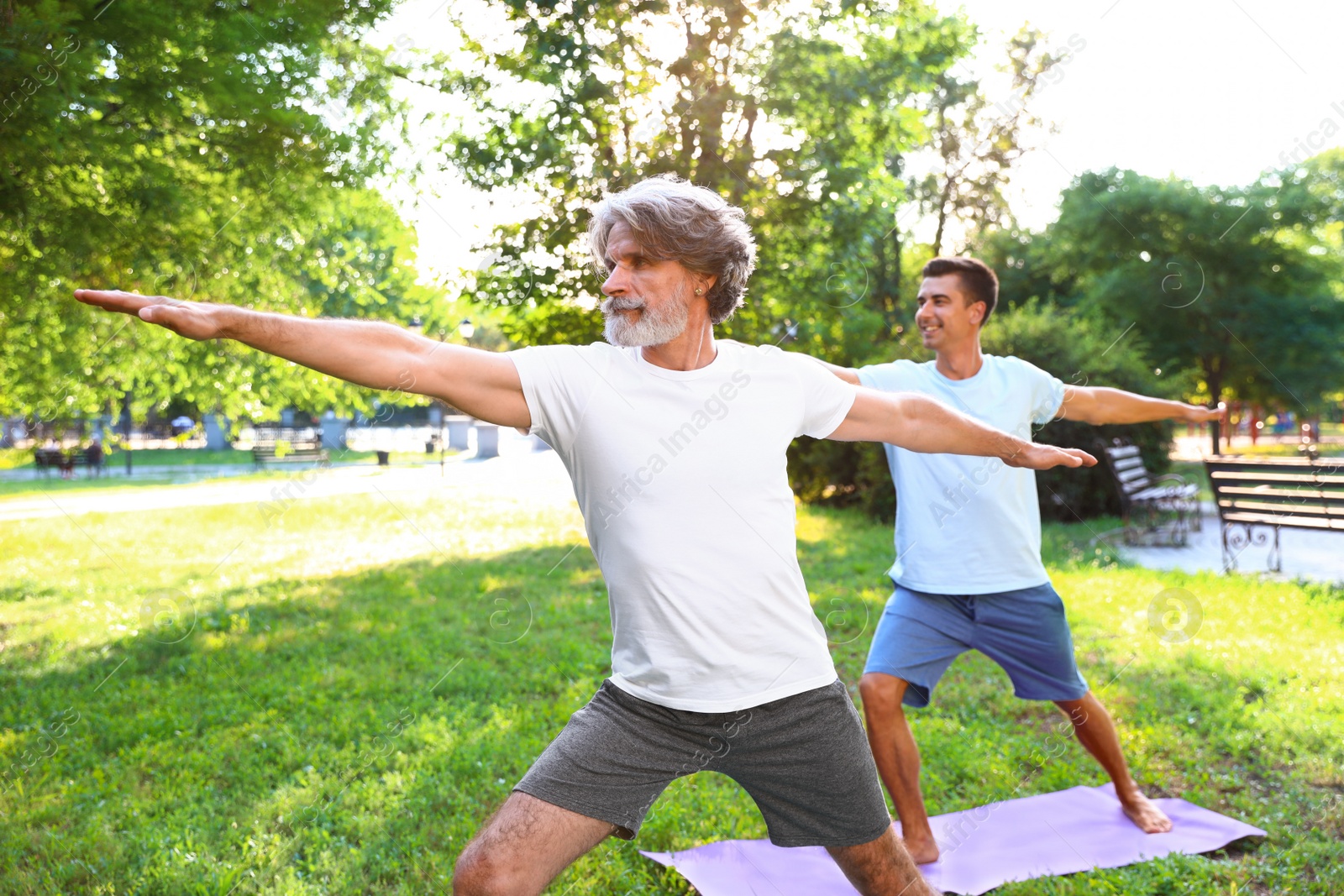Photo of Men practicing morning yoga in sunny park