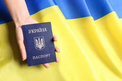 Photo of Woman holding Ukrainian internal passport on national flag, closeup with space for text