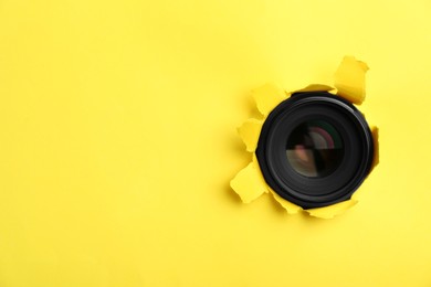 Photo of Hidden camera lens through hole in yellow paper. Space for text