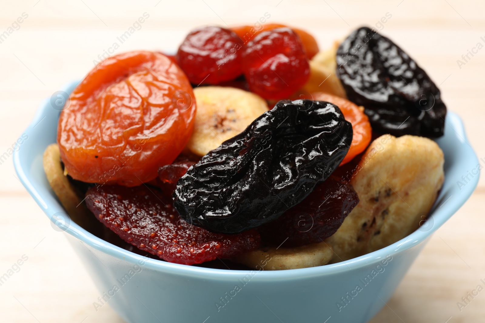 Photo of Mix of delicious dried fruits on white wooden table, closeup