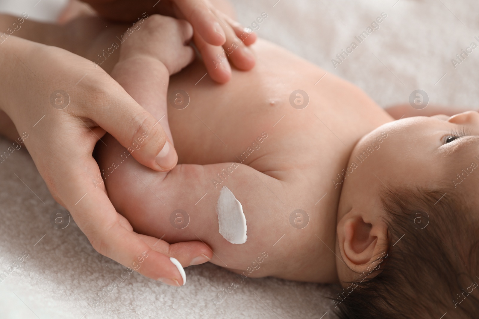 Photo of Mother applying body cream on her little baby, closeup