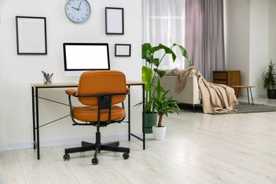 Photo of Stylish room interior with comfortable office chair, desk and houseplants