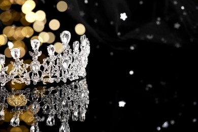 Image of Beautiful silver tiara with diamonds on dark mirror surface, space for text. Bokeh effect