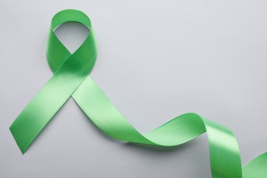 World Mental Health Day. Green ribbon on color background, top view