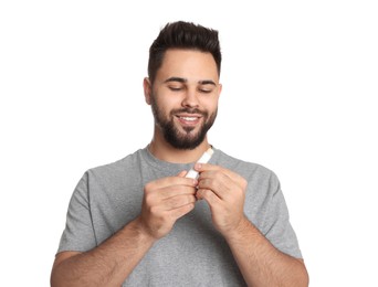 Photo of Young man with lip balm on white background