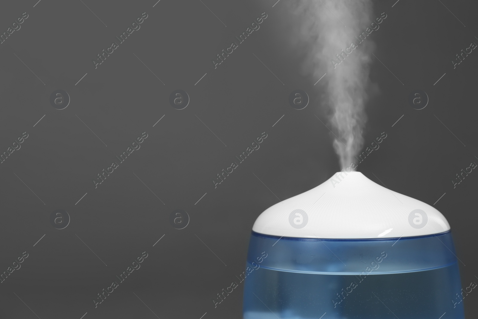 Photo of Modern air humidifier on grey background, closeup. Space for text