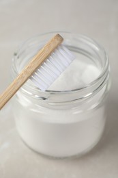 Photo of Bamboo toothbrush and jar of baking soda on light table, closeup