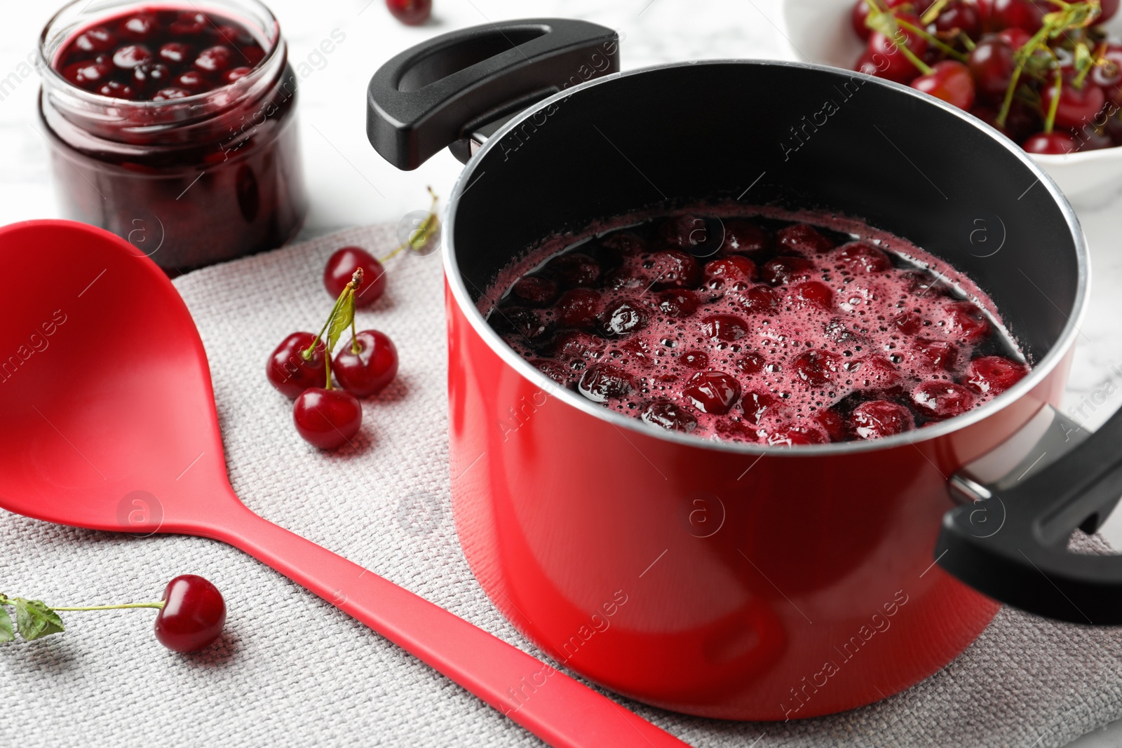 Photo of Pot with cherries in sugar syrup on table. Making delicious jam