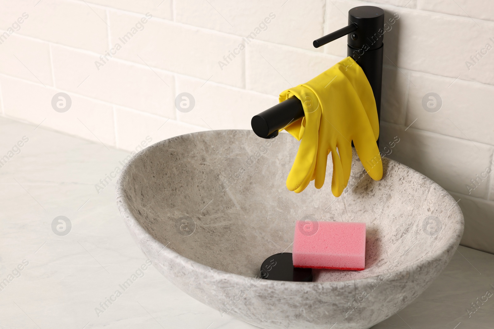 Photo of Rubber gloves on faucet in bathroom sink