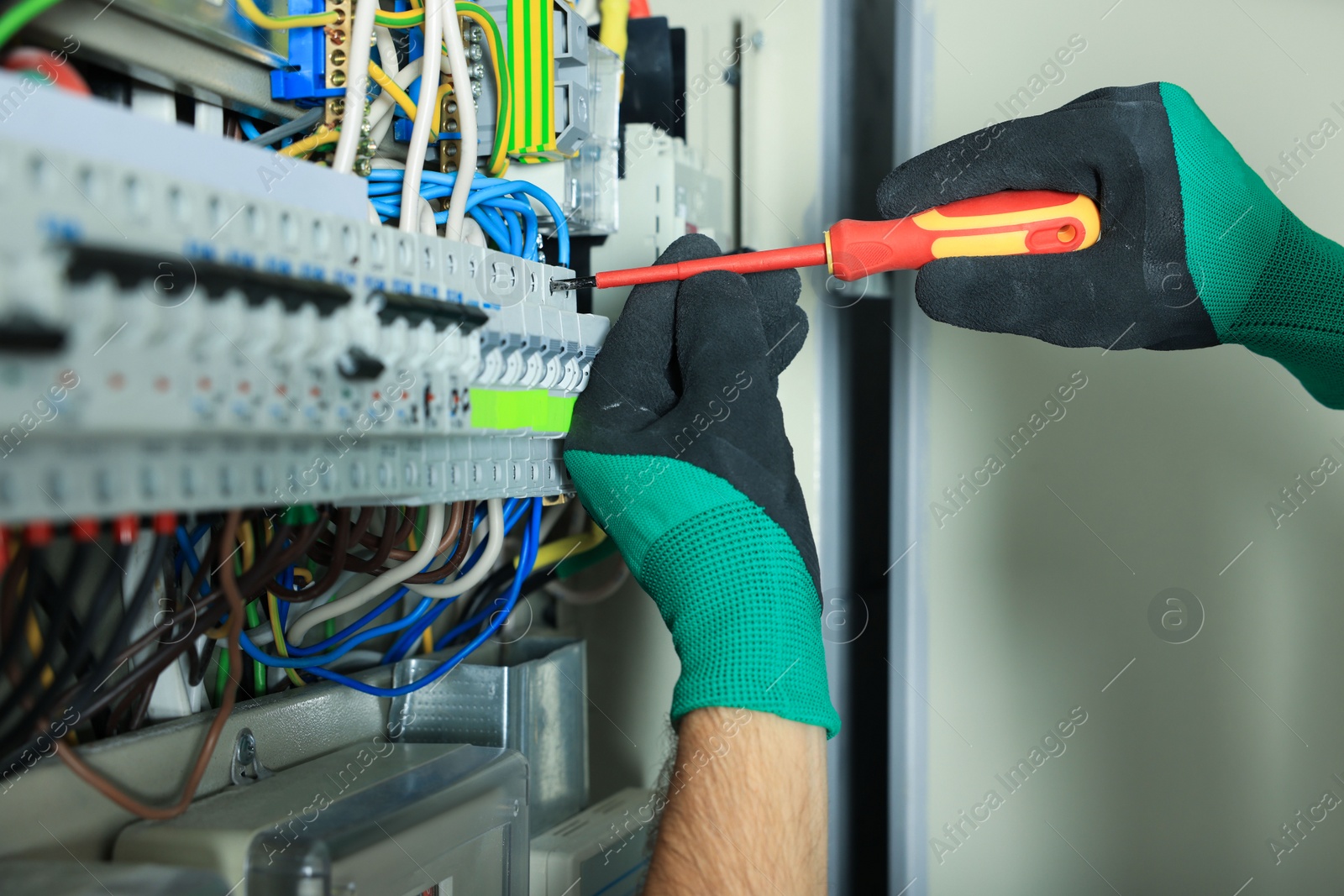 Photo of Electrician repairing fuse box with screwdriver, closeup