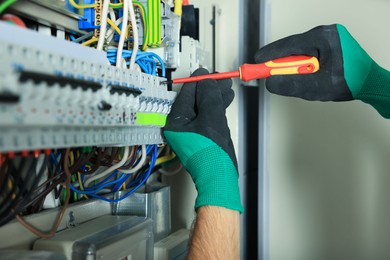 Photo of Electrician repairing fuse box with screwdriver, closeup