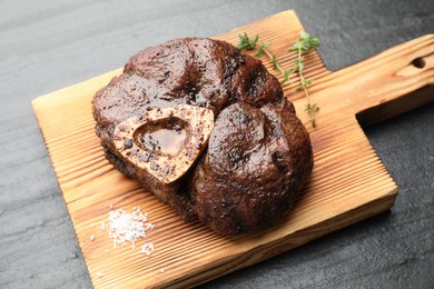 Photo of Piece of delicious grilled beef meat, thyme and salt on black table