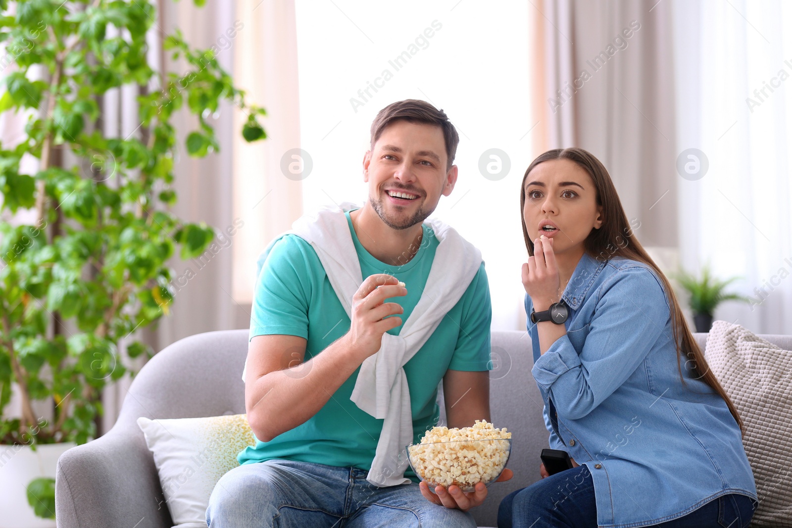 Photo of Couple watching movie with popcorn in living room