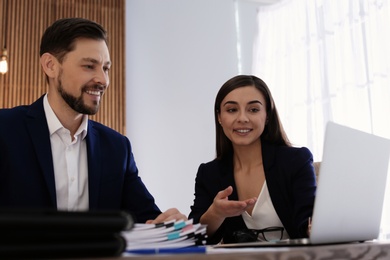 Photo of Office employees working with laptop and documents at table indoors