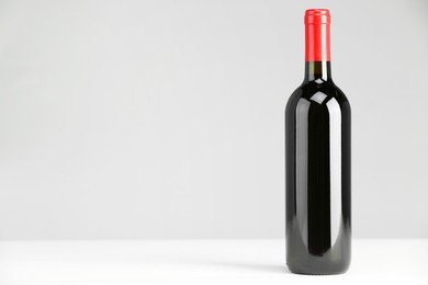 Photo of Bottle of expensive red wine on white table. Space for text