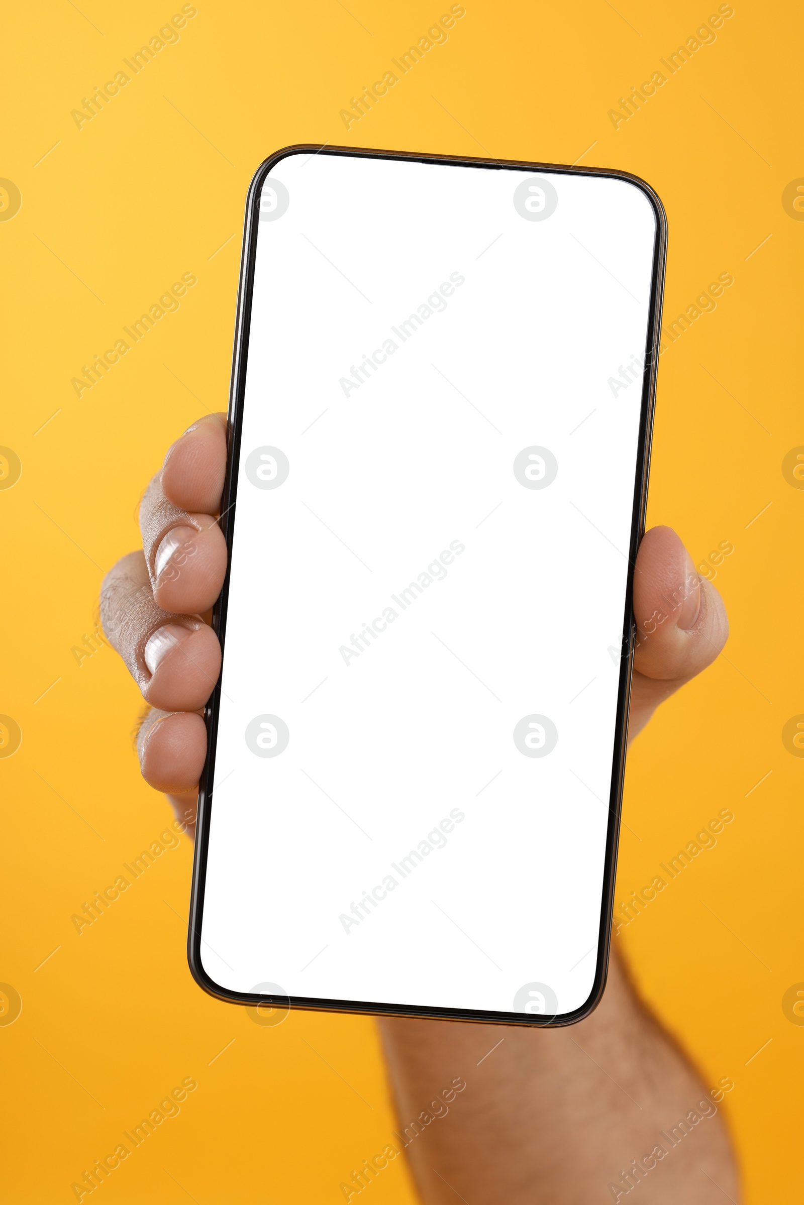 Photo of Man holding smartphone with blank screen on yellow background, closeup