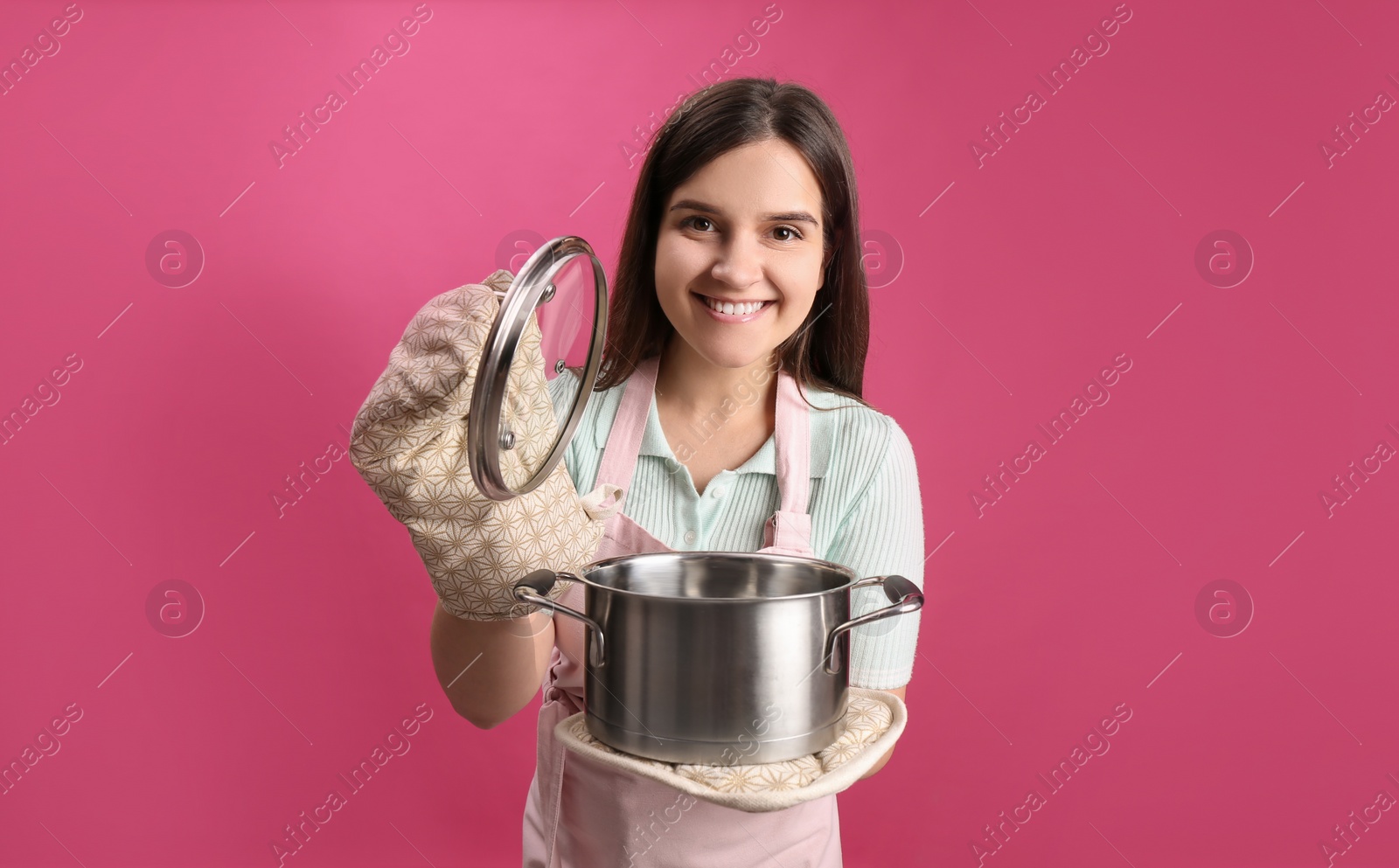 Photo of Happy young woman with cooking pot on pink background