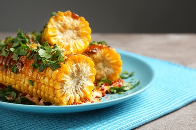 Plate with delicious grilled corn cobs and parsley on table, closeup