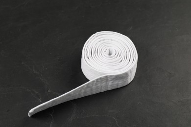 Photo of Rolled white karate belt on gray background