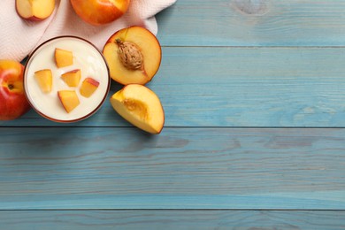 Photo of Tasty peach yogurt with pieces of fruit in glass on light blue wooden table. Space for text
