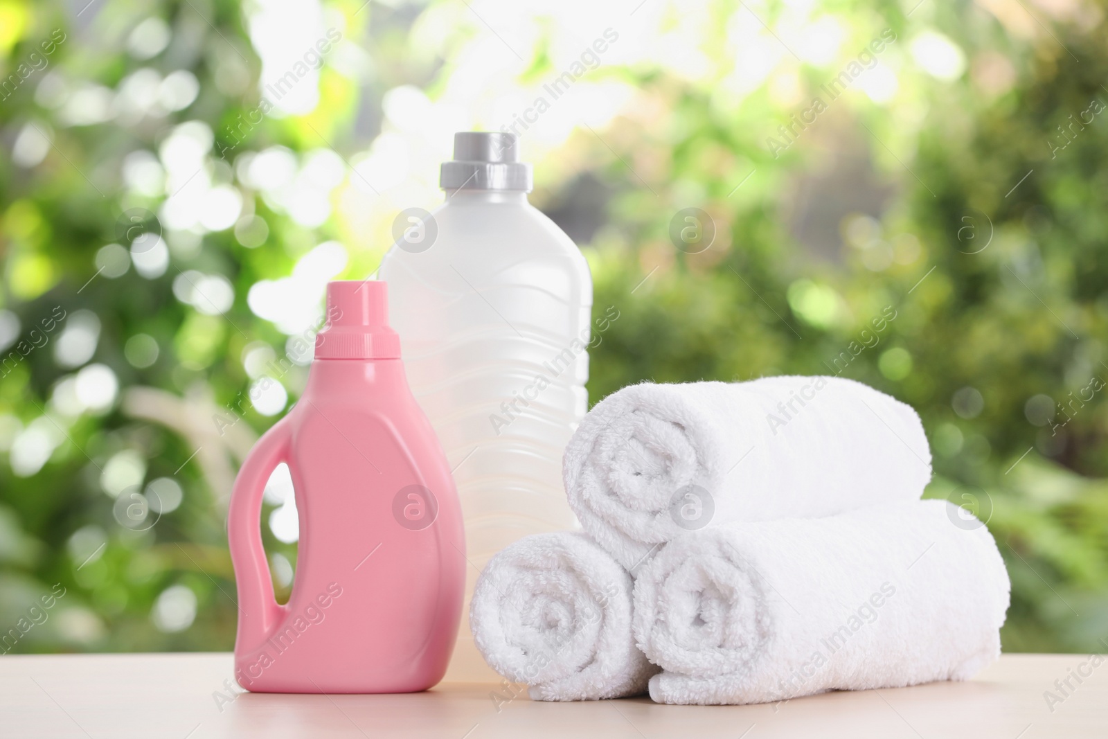 Photo of Soft bath towels and laundry detergents on table against blurred background