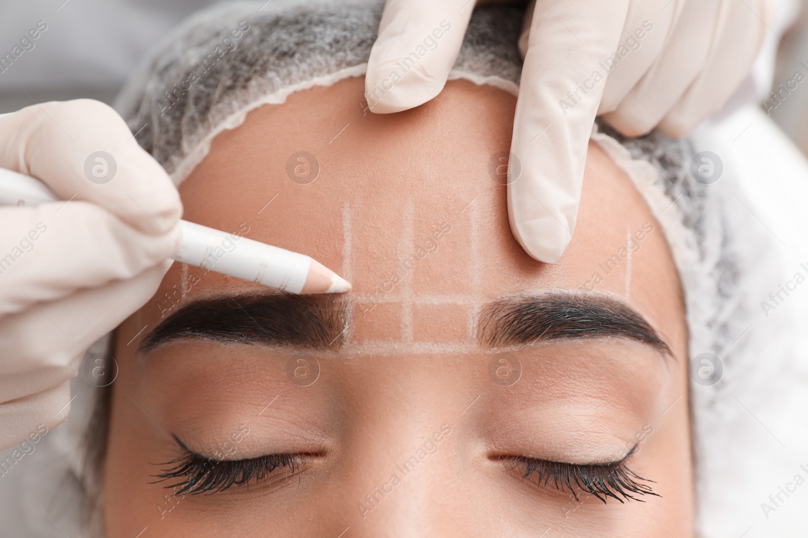 Photo of Young woman getting prepared for procedure of permanent eyebrow makeup in tattoo salon, closeup