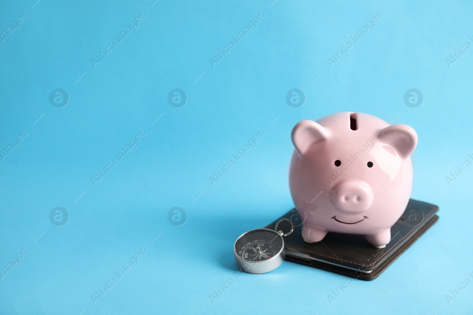 Photo of Piggy bank with passport and compass on color background, space for text. Travel agency