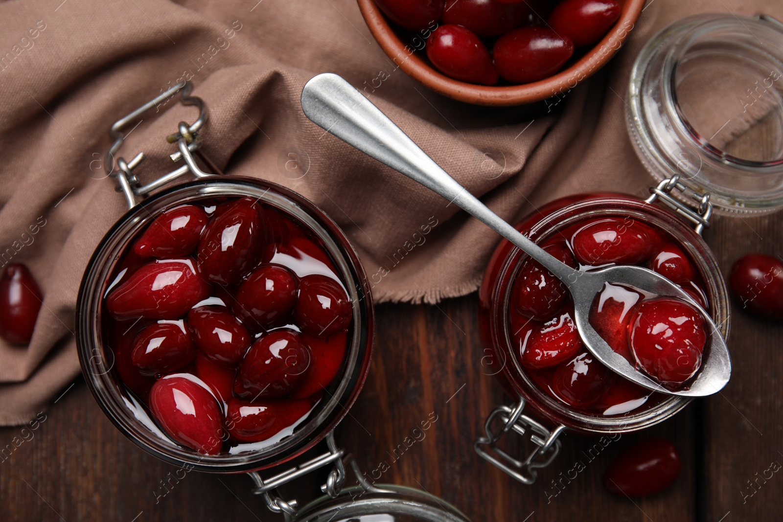 Photo of Delicious dogwood jam with berries on wooden table, flat lay