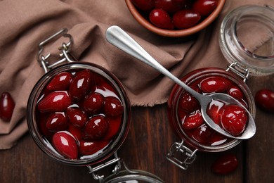 Photo of Delicious dogwood jam with berries on wooden table, flat lay