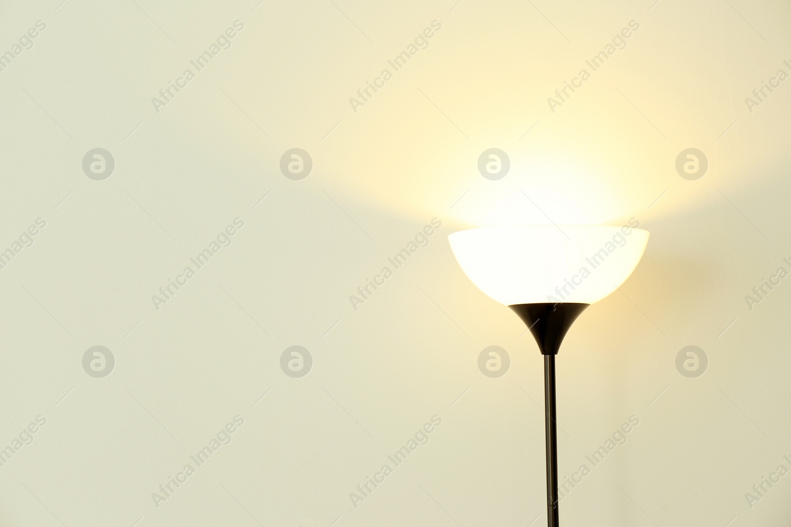 Photo of Modern floor lamp against light wall. Space for text