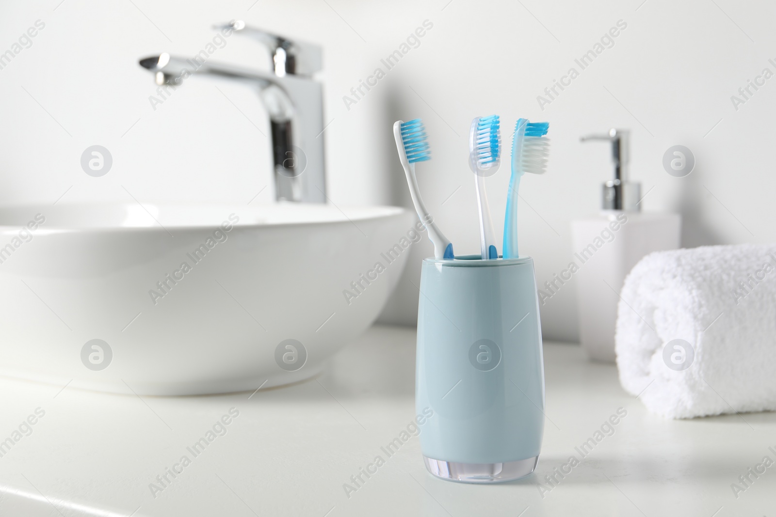Photo of Holder with plastic toothbrushes on white countertop in bathroom, space for text