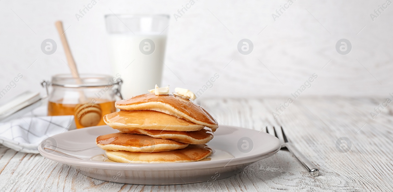 Image of Tasty pancakes with honey and butter on table. Banner design