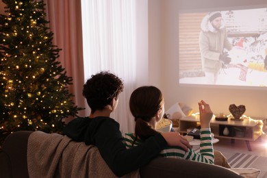 Photo of Couple watching romantic Christmas movie via video projector at home