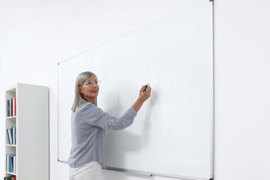 Photo of Professor explaining something at whiteboard in classroom, space for text
