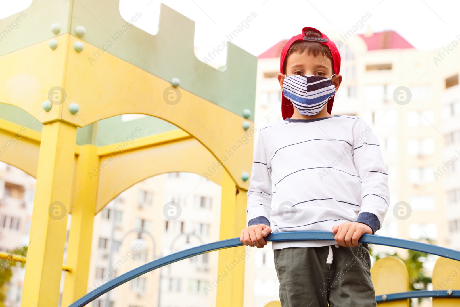 Photo of Little boy with medical face mask on playground during covid-19 quarantine