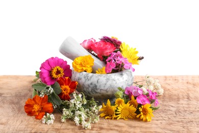 Marble mortar, pestle and different flowers on wooden table against white background