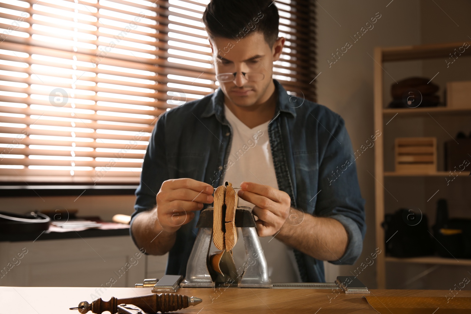 Photo of Man sewing piece of leather in workshop