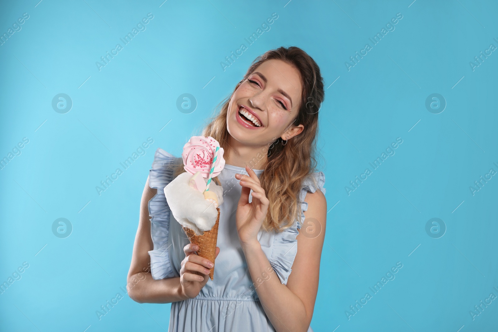 Photo of Portrait of young woman holding cotton candy dessert on blue background