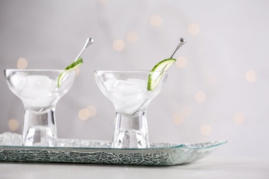 Photo of Glasses of martini with cucumber on table against light background. Space for text