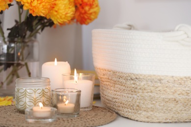 Photo of Beautiful burning candles, bag and flowers on table at home