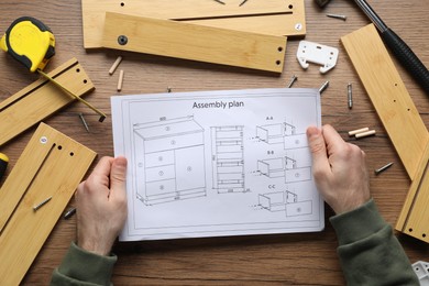 Photo of Man with furniture and assembly plan at wooden table, top view