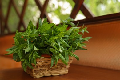 Photo of Beautiful green mint in wicker basket on wooden table, space for text