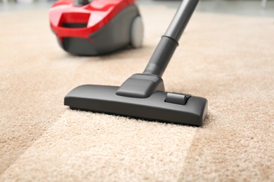 Image of Vacuuming dirty beige carpet. Clean area after using device, closeup