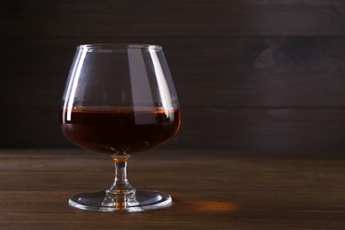 Delicious liqueur in glass on wooden table. Space for text