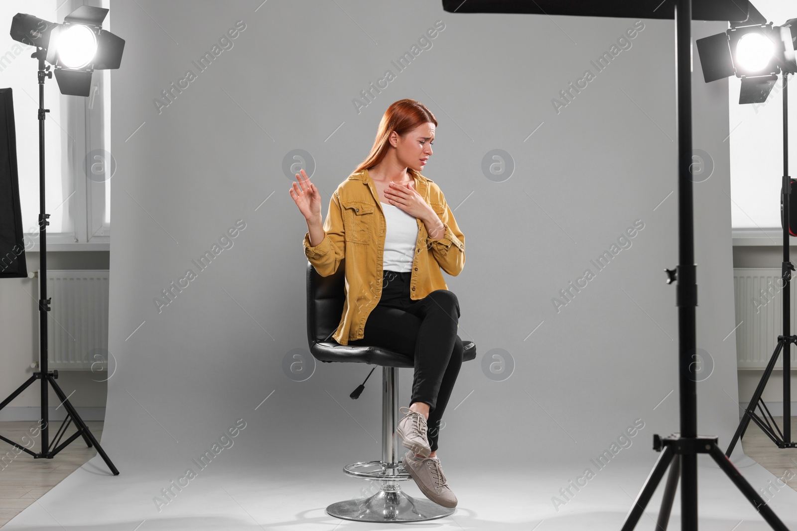 Photo of Casting call. Emotional woman performing on grey background in studio