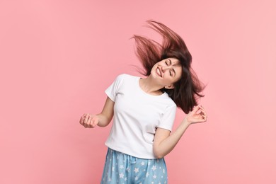 Happy woman in pyjama shaking head on pink background